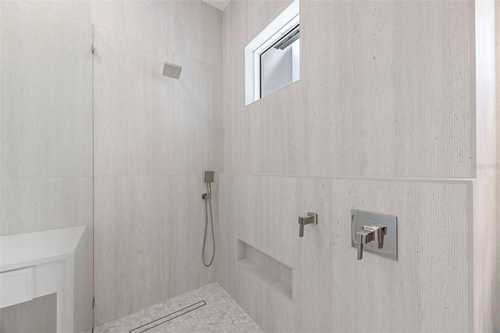 The luxurious primary suite offers a spa-inspired retreat featuring a freestanding soaking tub, oversized walk-in shower with rain head and handheld shower, premium Italian tile, designer fixtures, and thoughtful custom details throughout. - 1336 HAYS RD, TARPON SPRINGS