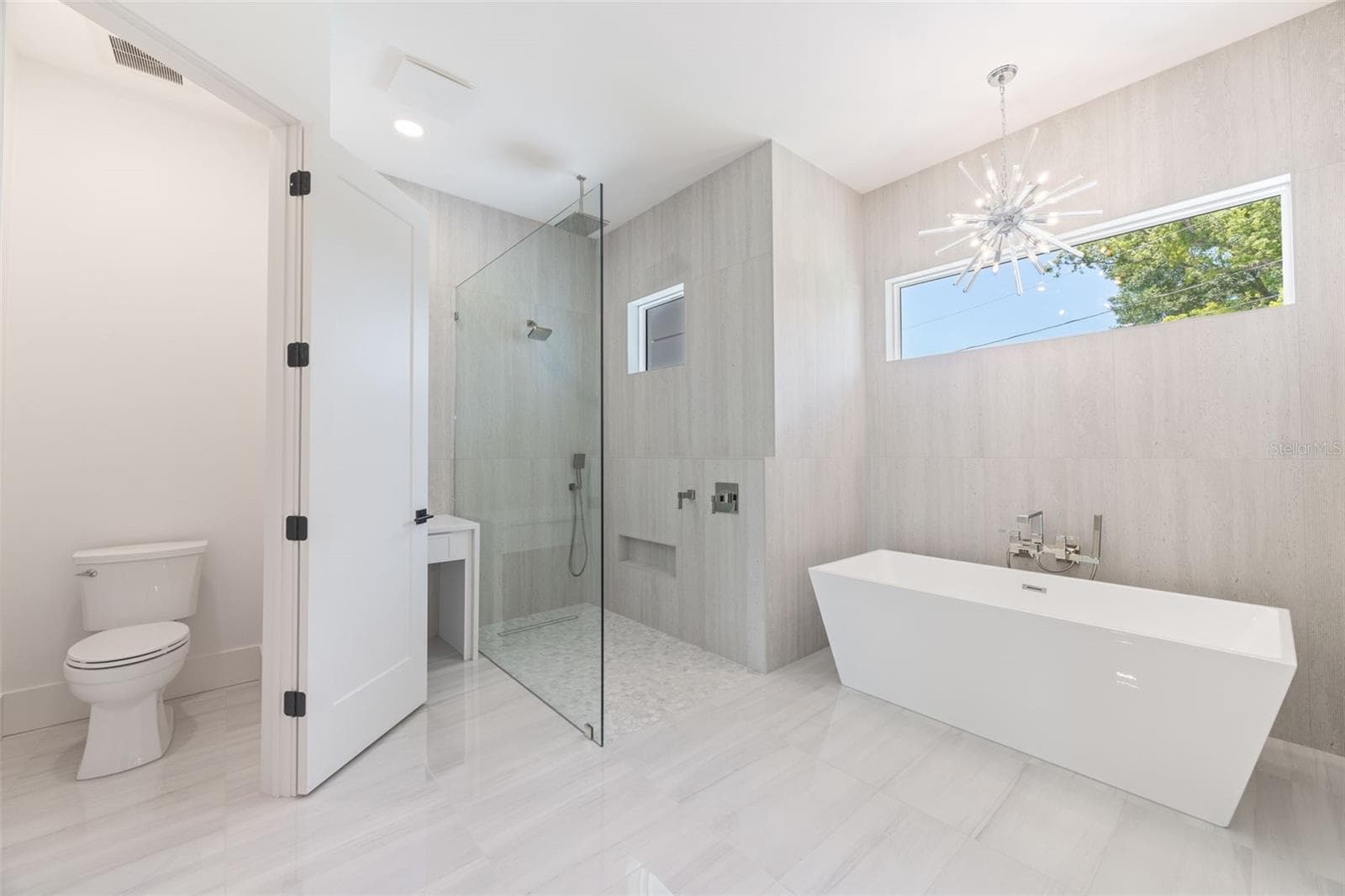 The luxurious primary suite offers a spa-inspired retreat featuring a freestanding soaking tub, oversized walk-in shower with rain head and handheld shower, premium Italian tile, designer fixtures, and thoughtful custom details throughout. - 1336 HAYS RD, TARPON SPRINGS