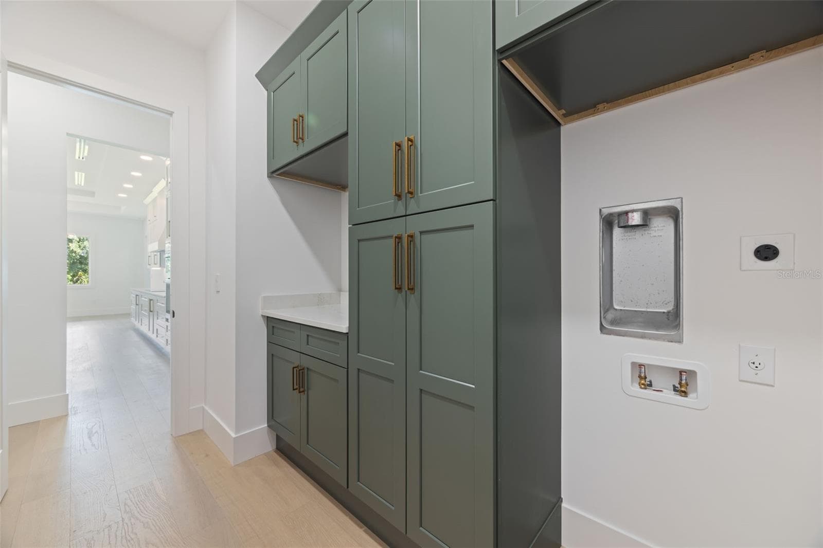 Designed with both beauty and functionality in mind, the laundry room offers elegant Shaker Ivy cabinetry, abundant storage with tall cabinets, stackable washer and dryer hookups, and a pre-plumbed sink base cabinet. - 1336 HAYS RD, TARPON SPRINGS