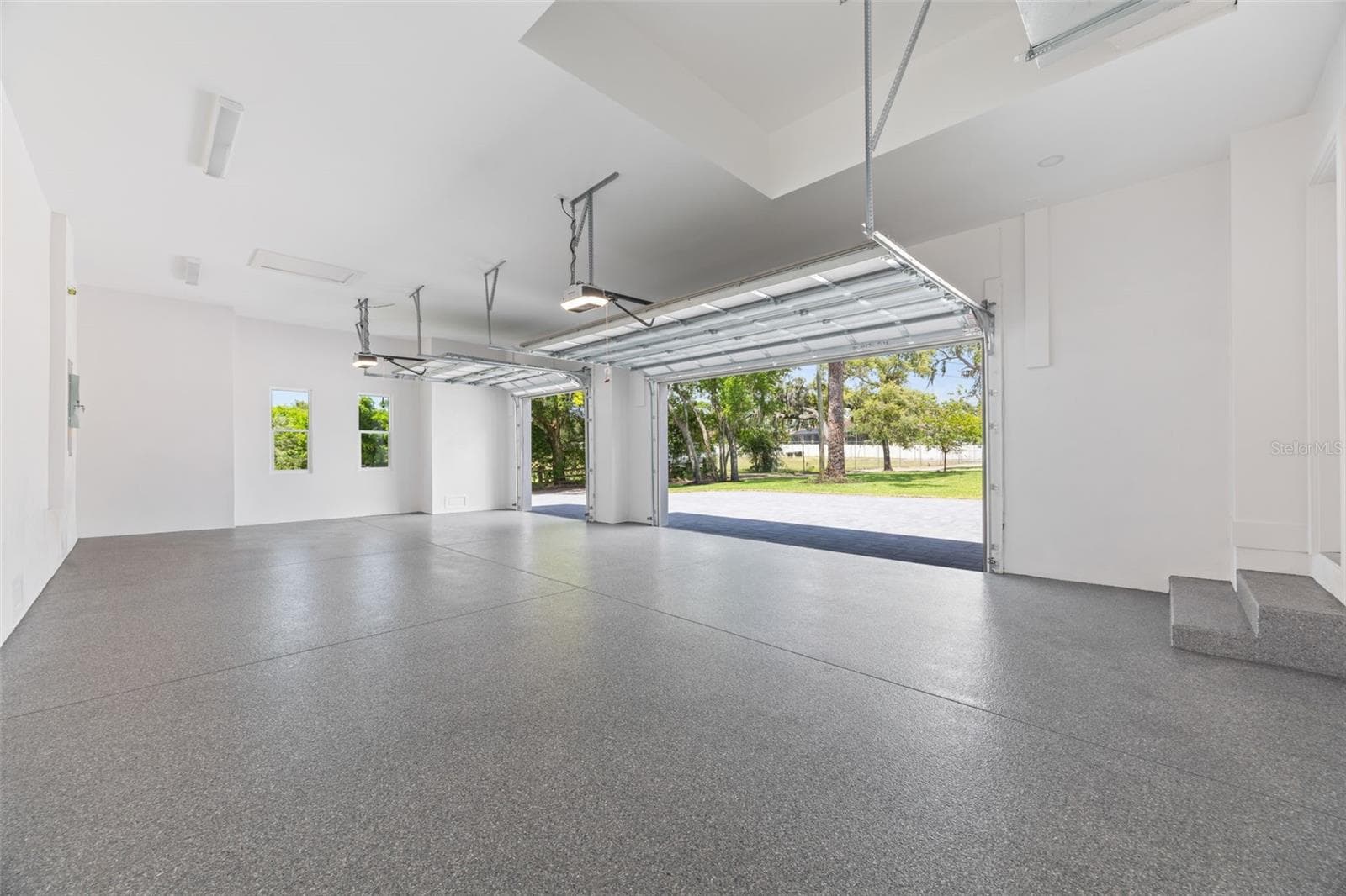 Oversized 3-car garage with industrial-grade epoxy flooring, Wi-Fi garage door openers, and impressive 11-foot ceilings. - 1336 HAYS RD, TARPON SPRINGS