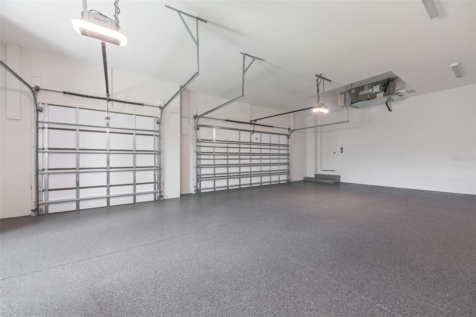 Oversized 3-car garage with industrial-grade epoxy flooring, Wi-Fi garage door openers, and impressive 11-foot ceilings. - 1336 HAYS RD, TARPON SPRINGS
