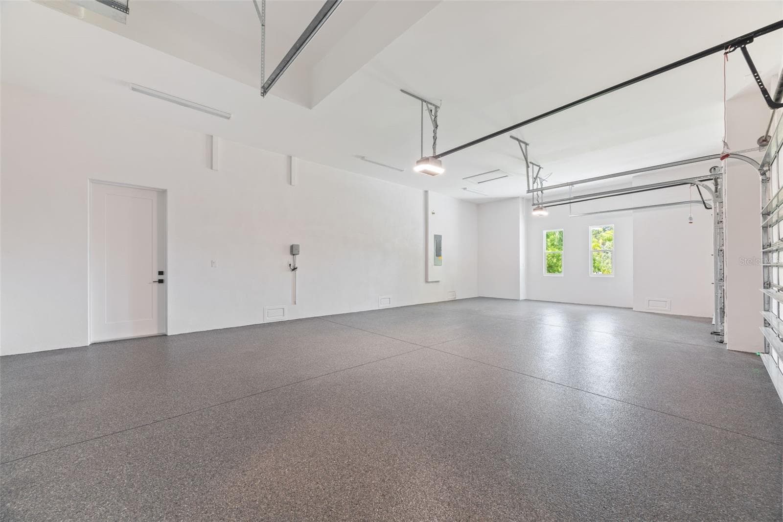 Oversized 3-car garage with industrial-grade epoxy flooring, Wi-Fi garage door openers, and impressive 11-foot ceilings. - 1336 HAYS RD, TARPON SPRINGS