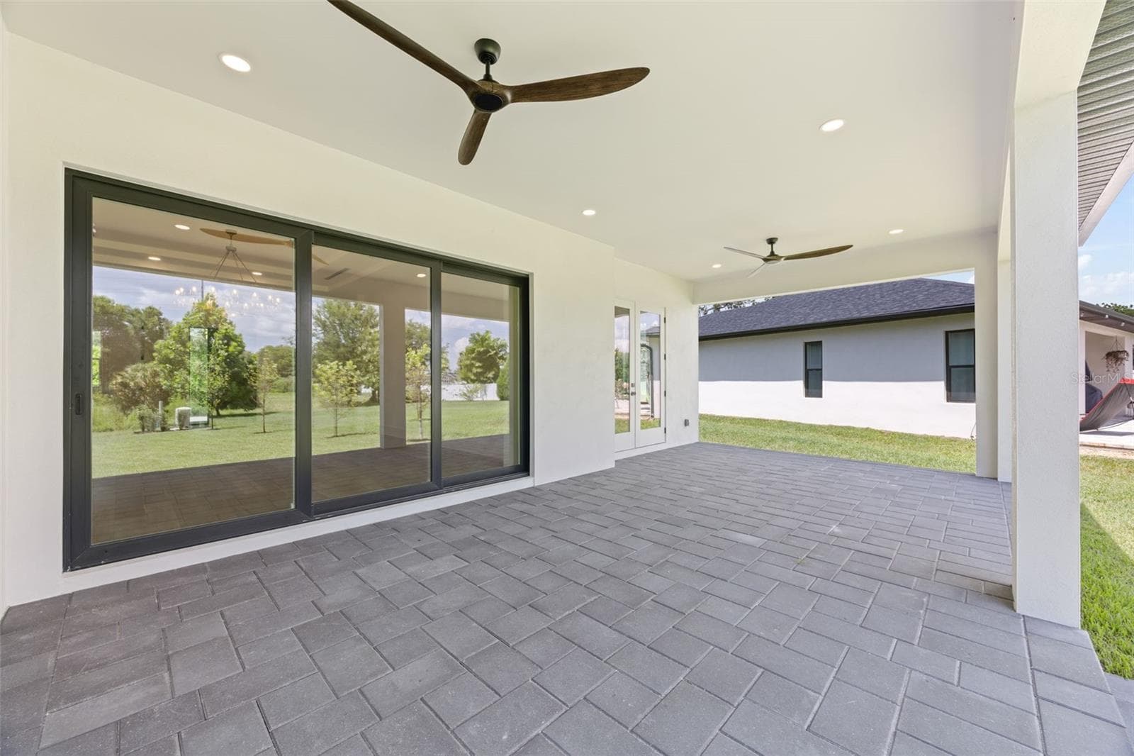 Covered paver lanai, pre-plumbed for a future outdoor kitchen, overlooking the beautifully landscaped yard with premium St. Augustine sod and mature native pine trees. - 1336 HAYS RD, TARPON SPRINGS