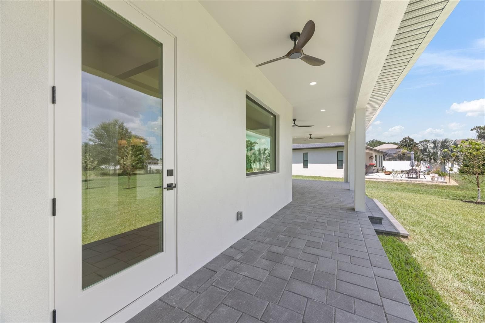Covered paver lanai, pre-plumbed for a future outdoor kitchen, overlooking the beautifully landscaped yard with premium St. Augustine sod and mature native pine trees. - 1336 HAYS RD, TARPON SPRINGS