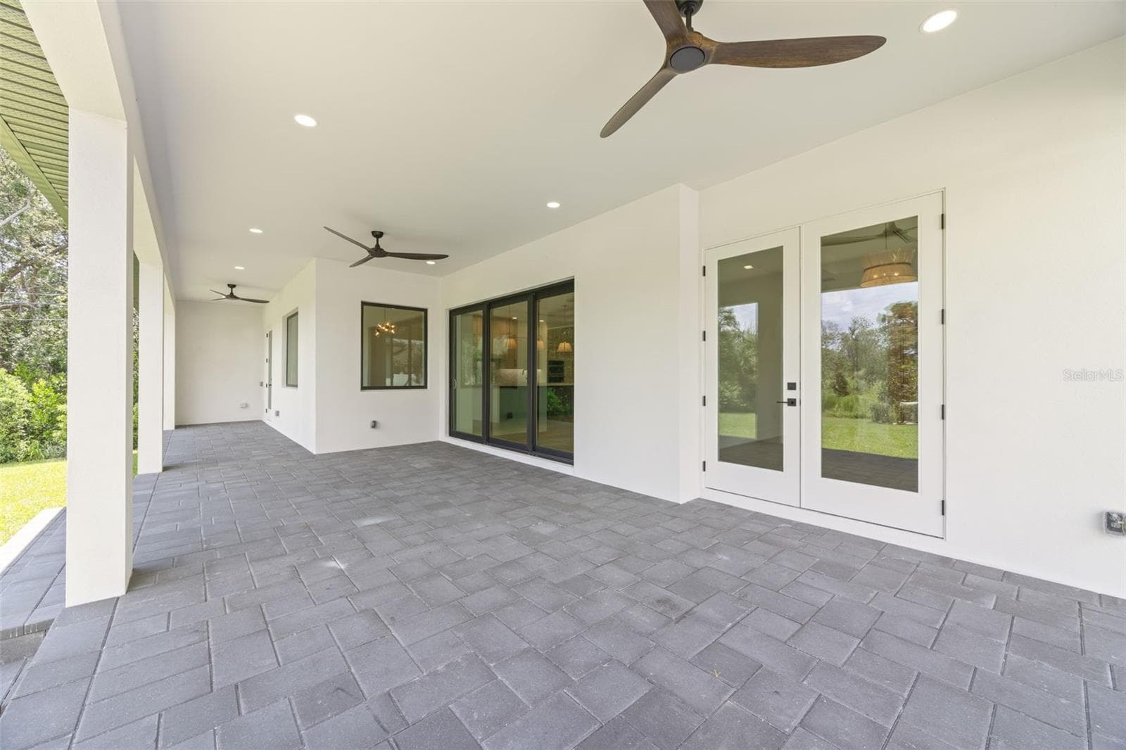 Covered paver lanai, pre-plumbed for a future outdoor kitchen, overlooking the beautifully landscaped yard with premium St. Augustine sod and mature native pine trees. - 1336 HAYS RD, TARPON SPRINGS