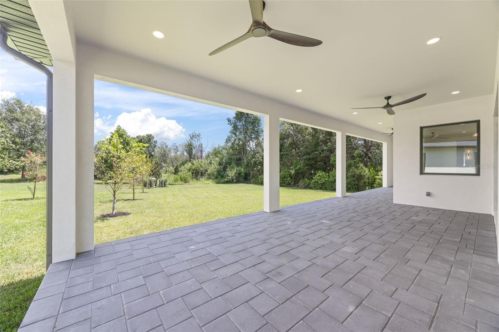 Covered paver lanai, pre-plumbed for a future outdoor kitchen, overlooking the beautifully landscaped yard with premium St. Augustine sod and mature native pine trees. - 1336 HAYS RD, TARPON SPRINGS
