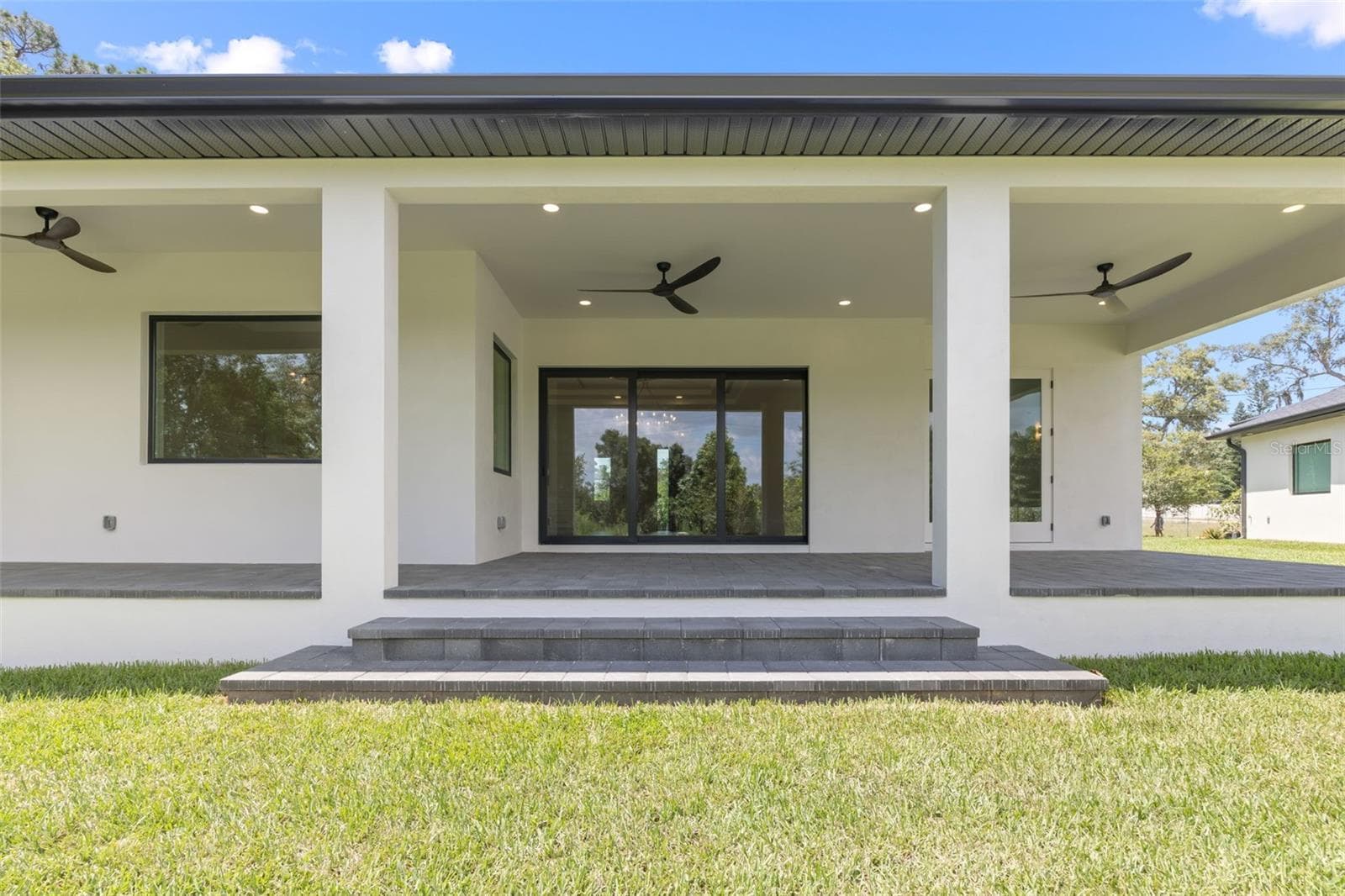 Covered paver lanai, pre-plumbed for a future outdoor kitchen, overlooking the beautifully landscaped yard with premium St. Augustine sod and mature native pine trees. - 1336 HAYS RD, TARPON SPRINGS