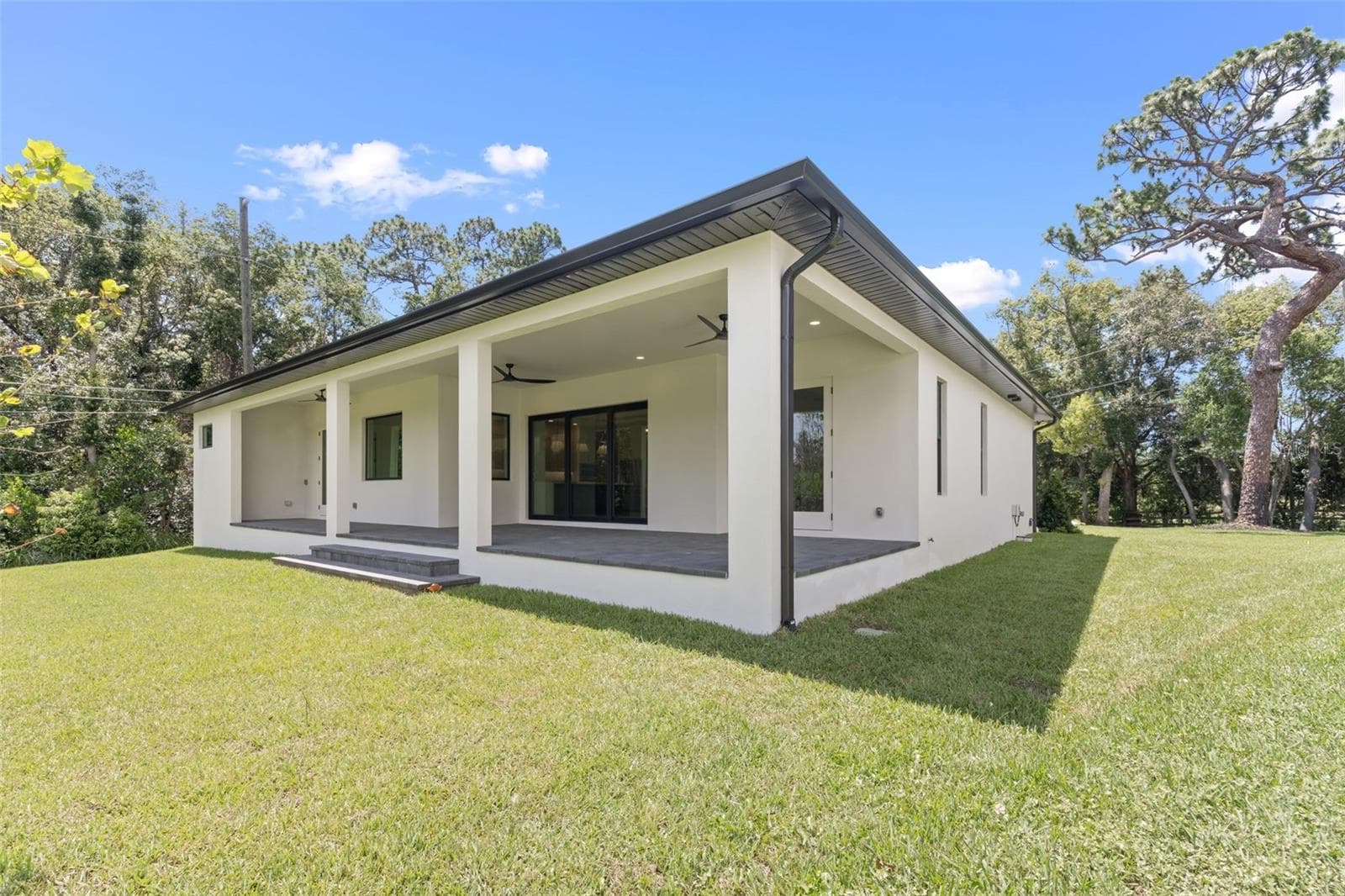 Covered paver lanai, pre-plumbed for a future outdoor kitchen, overlooking the beautifully landscaped yard with premium St. Augustine sod and mature native pine trees. - 1336 HAYS RD, TARPON SPRINGS
