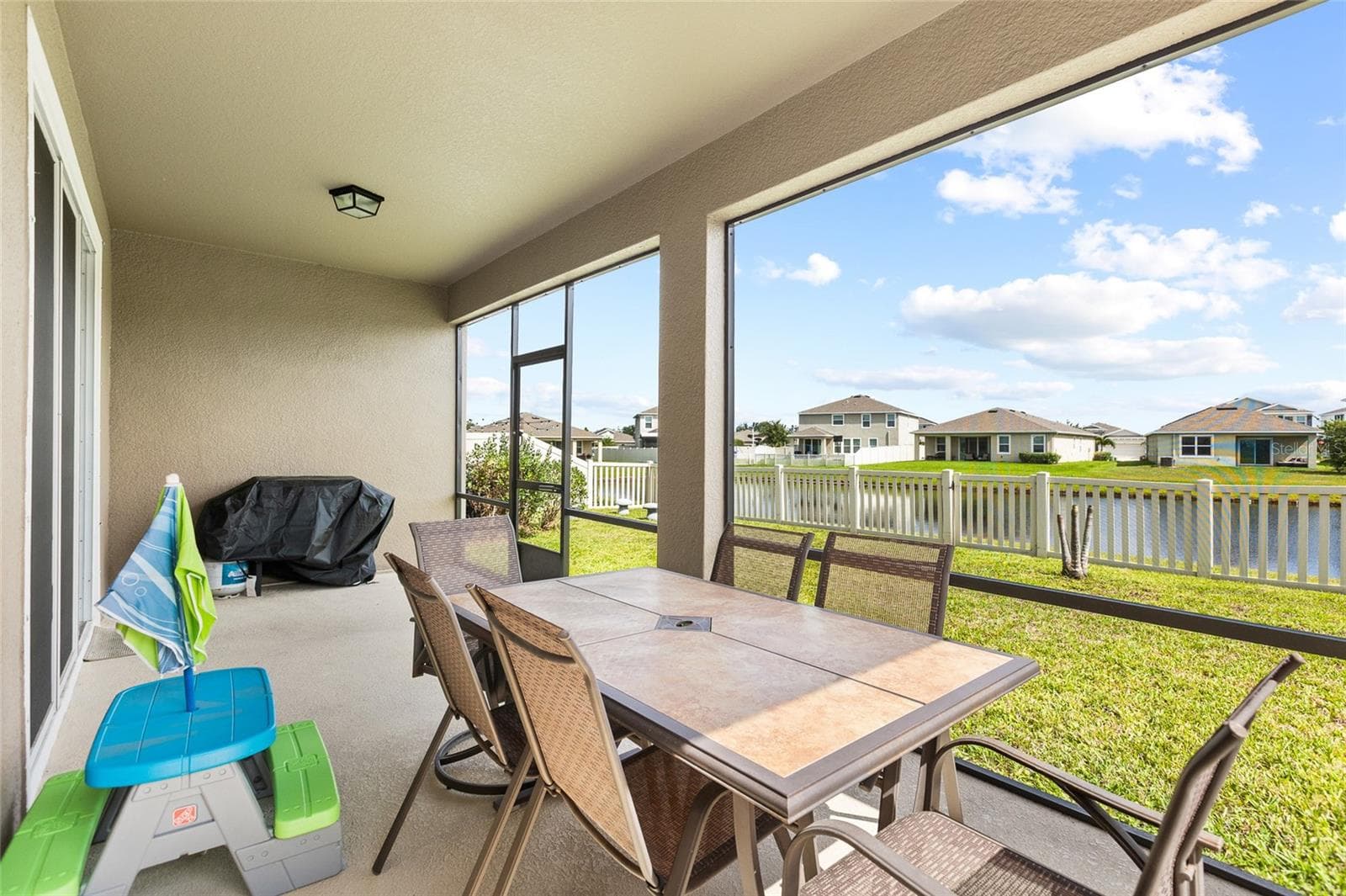 Enjoy Florida living year-round from the covered and screened lanai overlooking the pond. Whether you're enjoying your morning coffee, hosting friends, or unwinding after a long day, this outdoor living space provides beautiful water views and protection from the elements while maximizing your enjoyment of the outdoors. - 5025 JACKEL CHASE DR, WIMAUMA