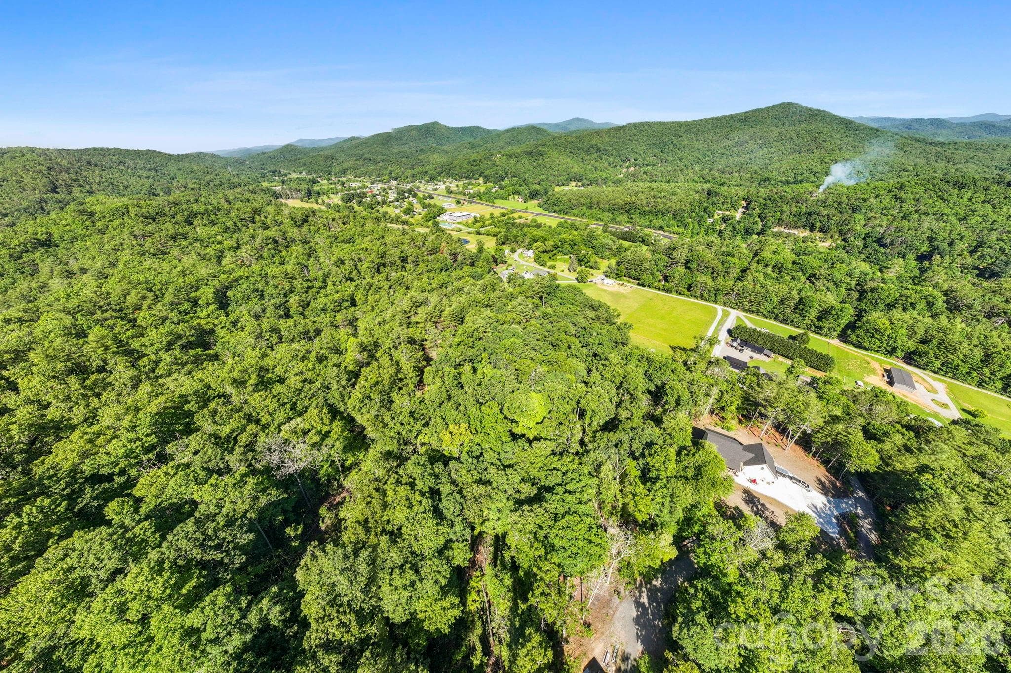 Soar above the beautiful woods that stretch across the landscape. This drone perspective reveals the vast, private acreage and the undulating topography leading up to the mountains. - Pisgah Forest