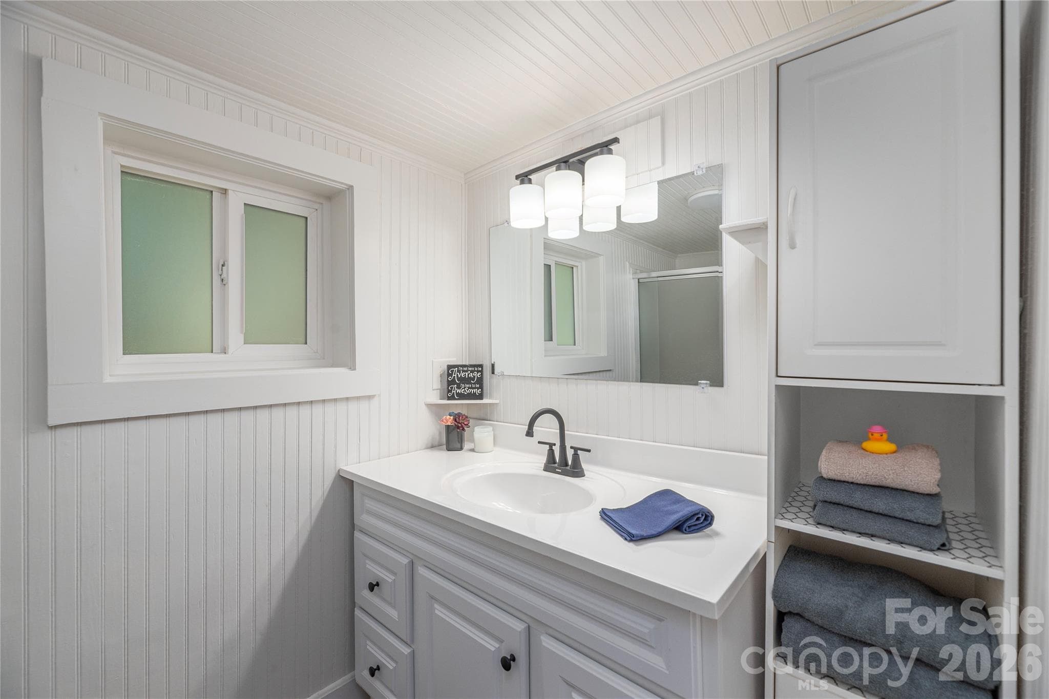 Updated bathroom featuring a modern vanity, fixtures, and beadboard accents. - Canton