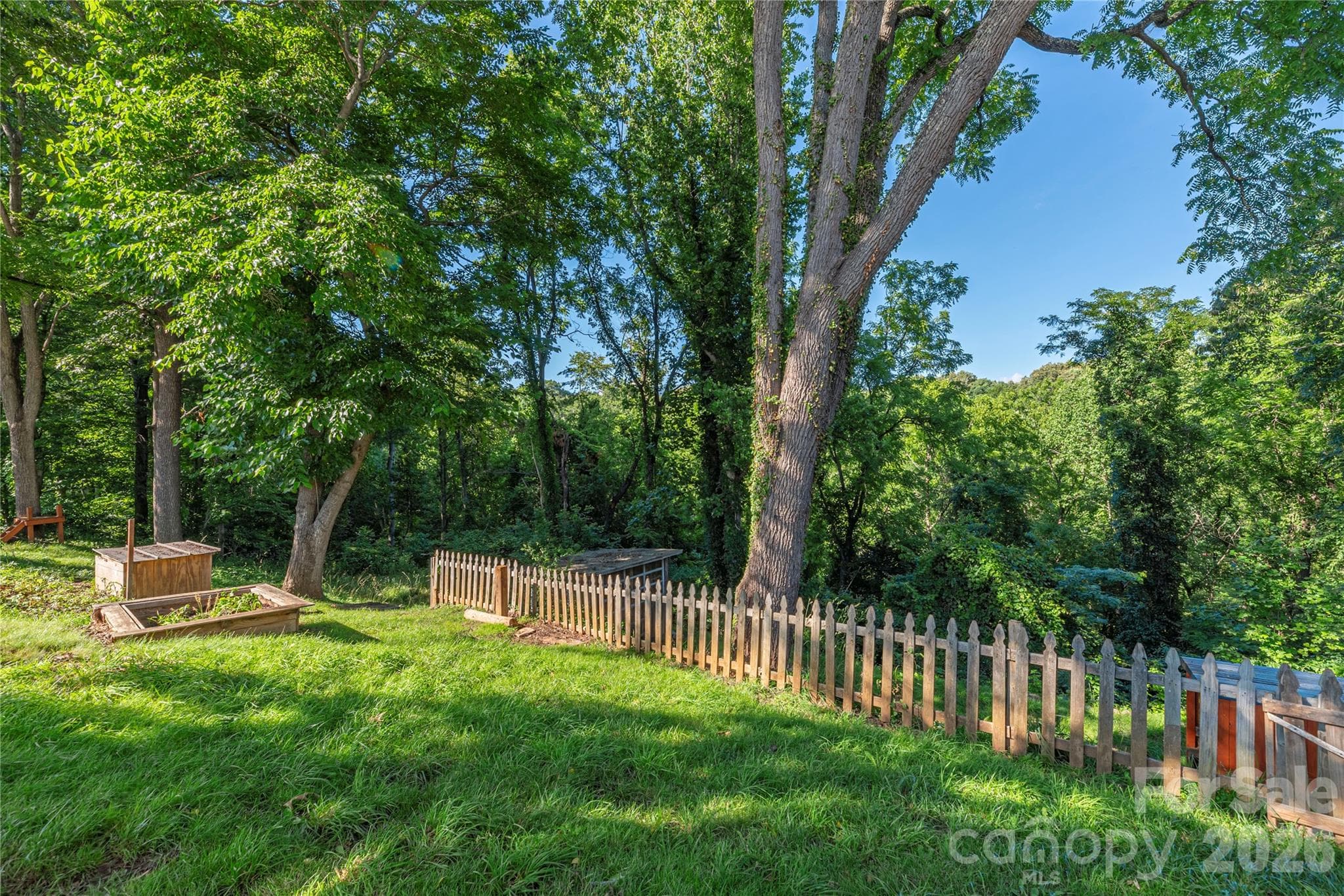 A raised garden bed and established trees create a peaceful backyard setting. - 261 Star Ridge Road, Canton