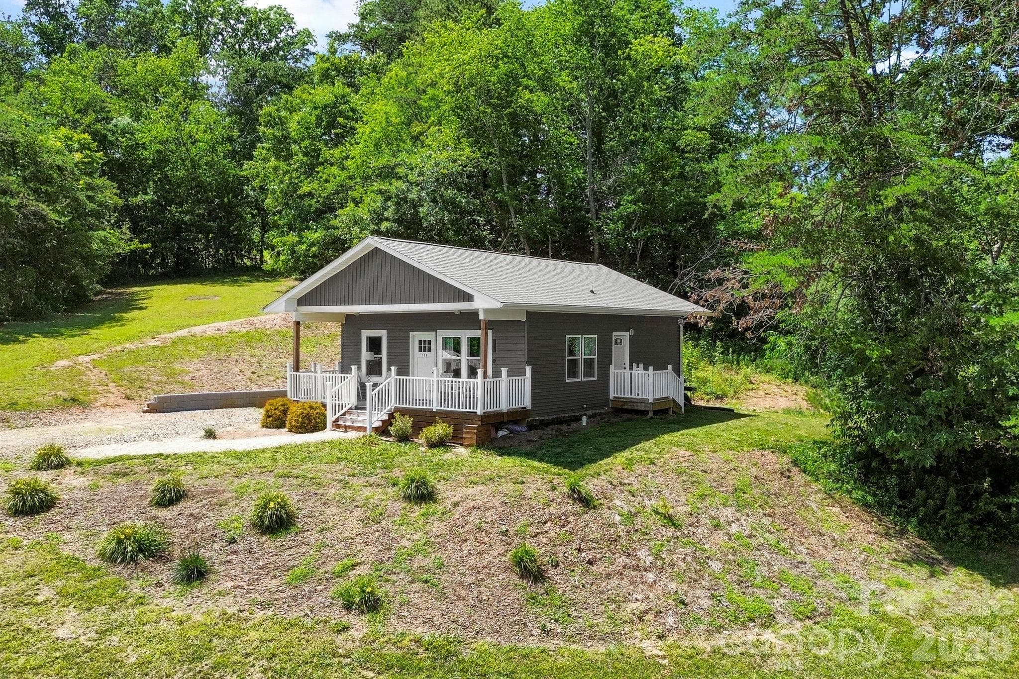 Aerial angle showcasing the home's setting, open yard space, and natural privacy. - Asheville