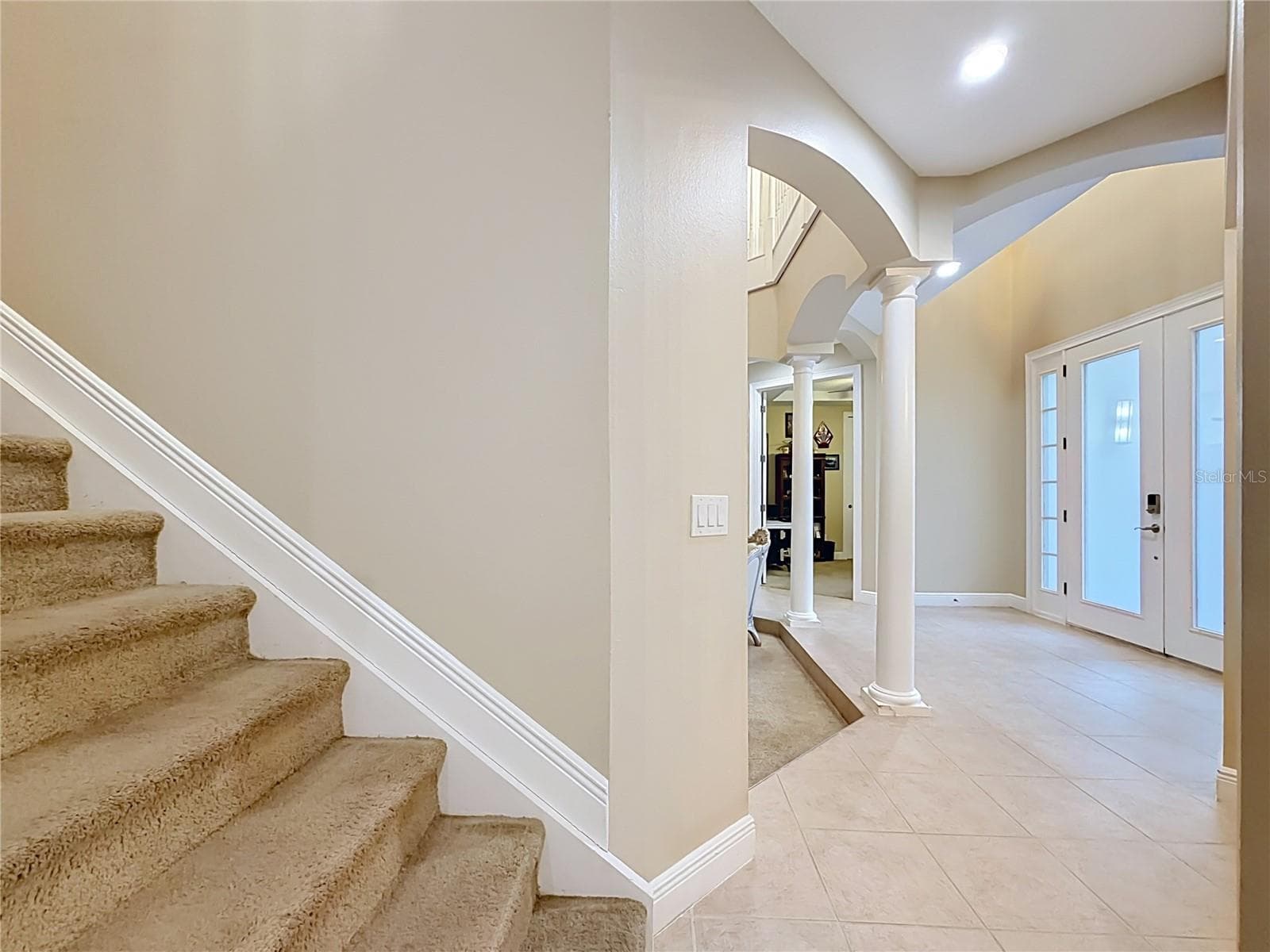 Staircase to 2nd floor and 4 more bedrooms. View of double door entry foyer with 2 architectural columns, 2 additional bedrooms, full bath, and one of two 2-car garages. - 3405 HEIRLOOM ROSE PL, OVIEDO