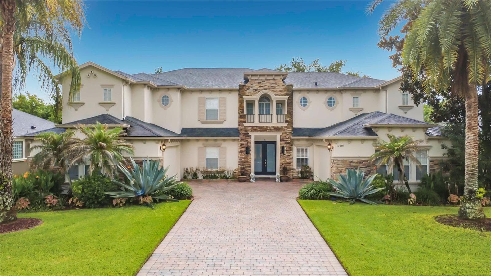 Exterior front of residence. Double door covered entry and two 2-car garages flanking paver driveway. - 3405 HEIRLOOM ROSE PL, OVIEDO