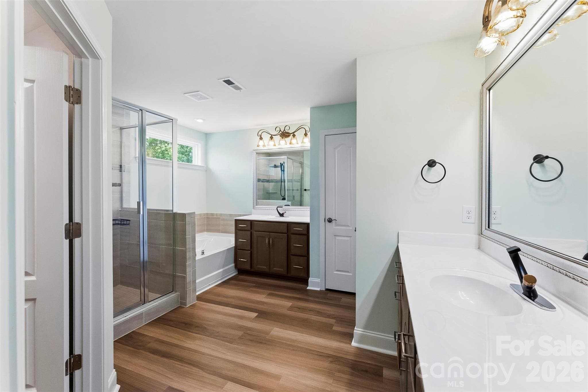 Primary Bathroom has standing glass shower, garden tub, dual vanities, upgraded vanities and faucets, lighting and mirrors.  Walk in Closet off of Primary Bathroom. - 1318 Poppy Way, Matthews
