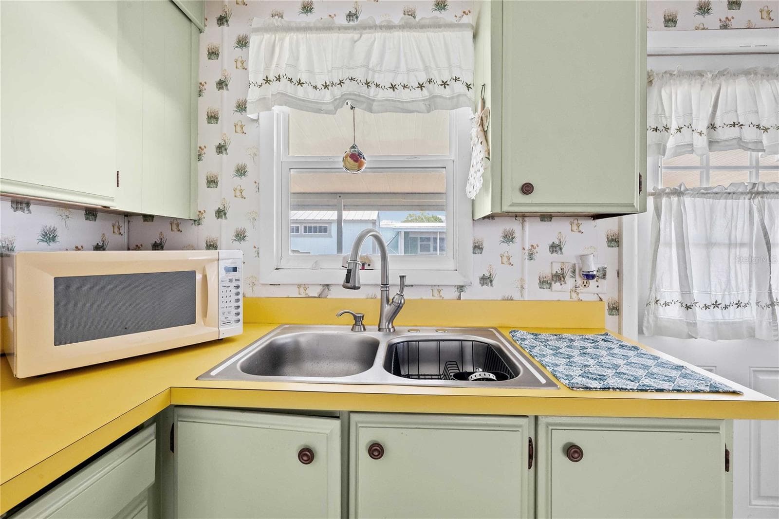 It has painted wood cabinets with a cheery yellow laminate top - 5301 FLINT ST, ZEPHYRHILLS