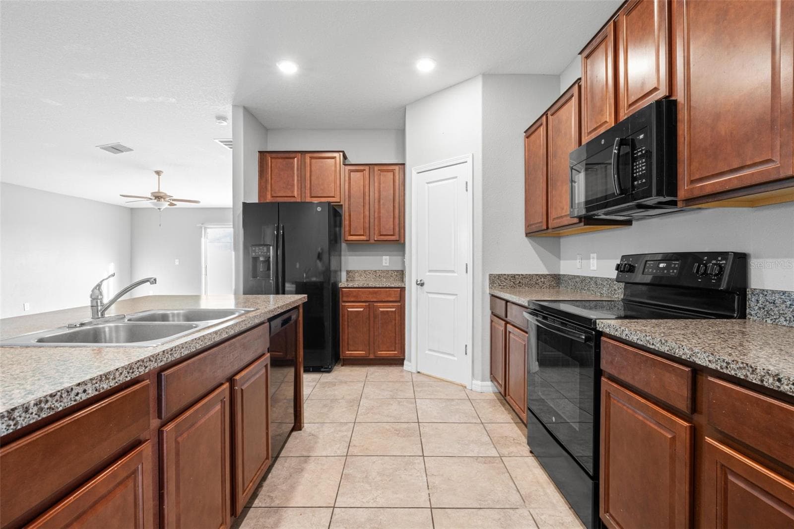 Granite countertops extend along both sides of the kitchen, providing generous prep space, abundant cabinetry, and an efficient layout designed to maximize functionality. - 6810 TRENT CREEK DR, SUN CITY CENTER