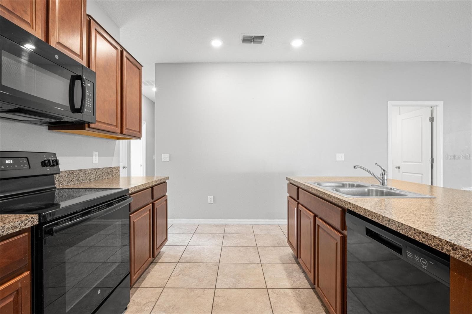 The oversized peninsula provides generous prep space, breakfast bar seating, and a double-basin stainless steel sink, creating a natural gathering place at the heart of the kitchen. - 6810 TRENT CREEK DR, SUN CITY CENTER