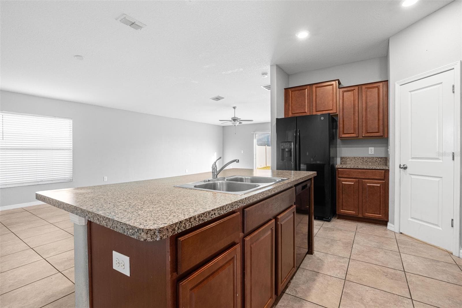 Kitchen with granite countertops, espresso cabinetry, a smooth-top electric range, built-in microwave, dishwasher, French door refrigerator with ice maker and water dispenser, plus a pantry for additional storage. - 6810 TRENT CREEK DR, SUN CITY CENTER