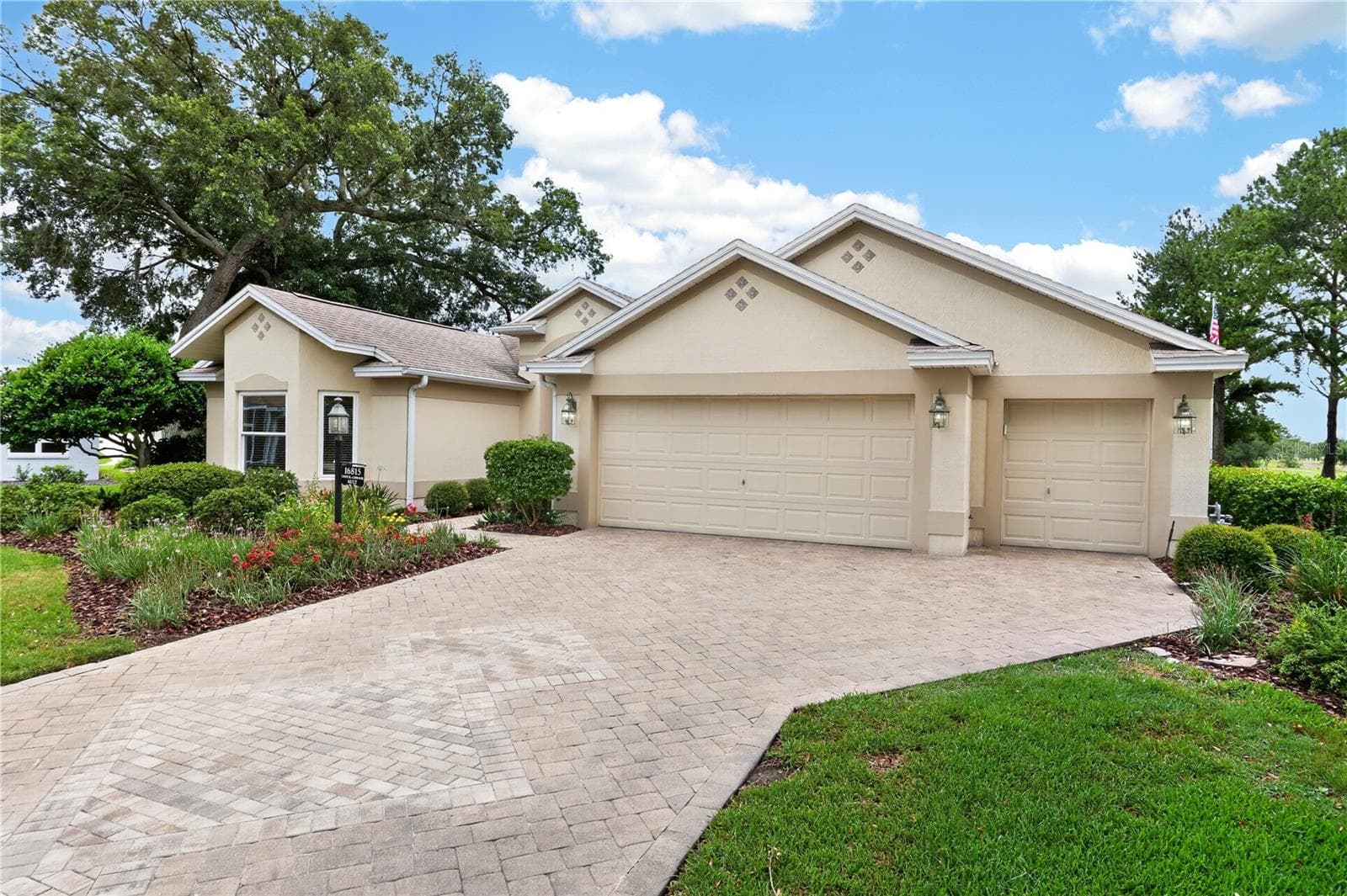 Front exterior view with broad driveway, two-car garage plus golf cart garage, mature landscaping, and attractive curb appeal. - 16815 SE 85TH BELKNAP AVE, THE VILLAGES