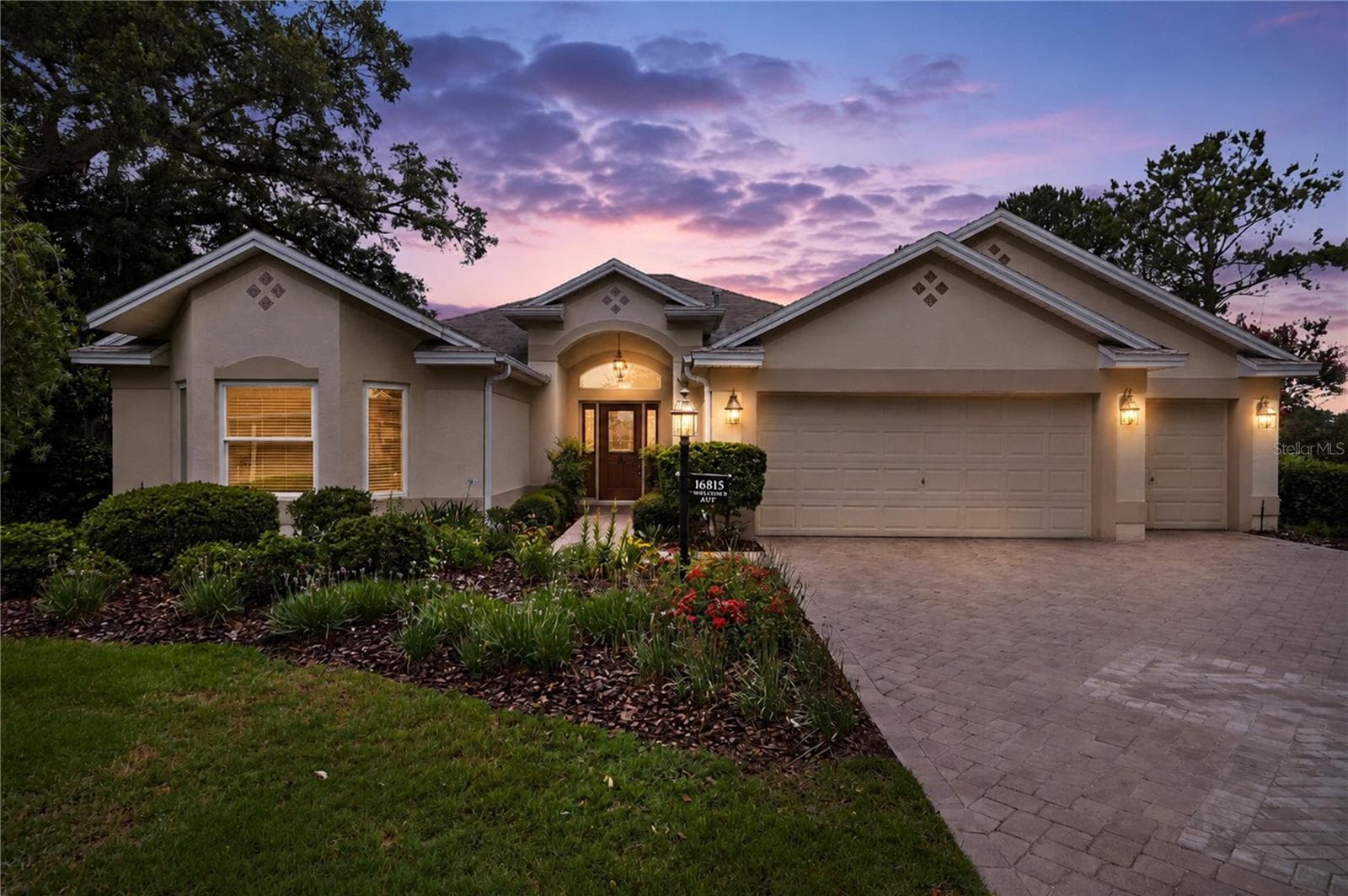 Evening exterior view showing the home beautifully lit at dusk, creating a warm and inviting first impression. - 16815 SE 85TH BELKNAP AVE, THE VILLAGES