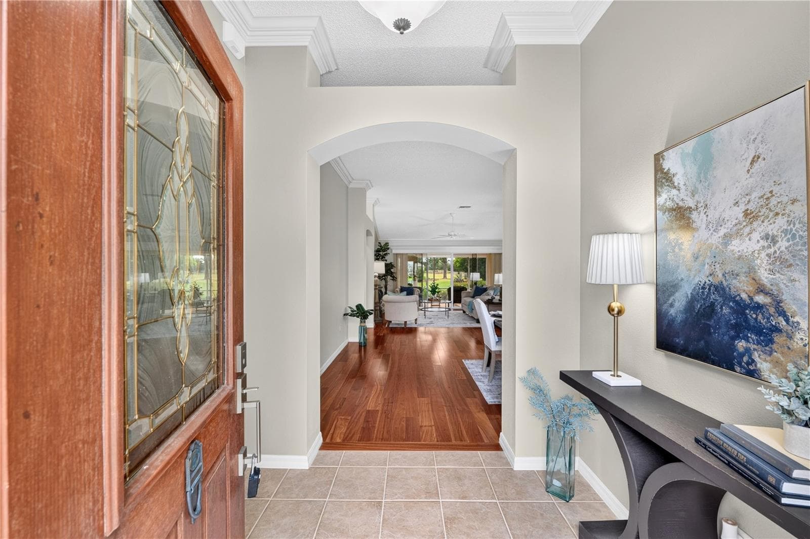 Spacious foyer with rich wood flooring, neutral tones, and a graceful arched opening leading into the main living areas. - 16815 SE 85TH BELKNAP AVE, THE VILLAGES