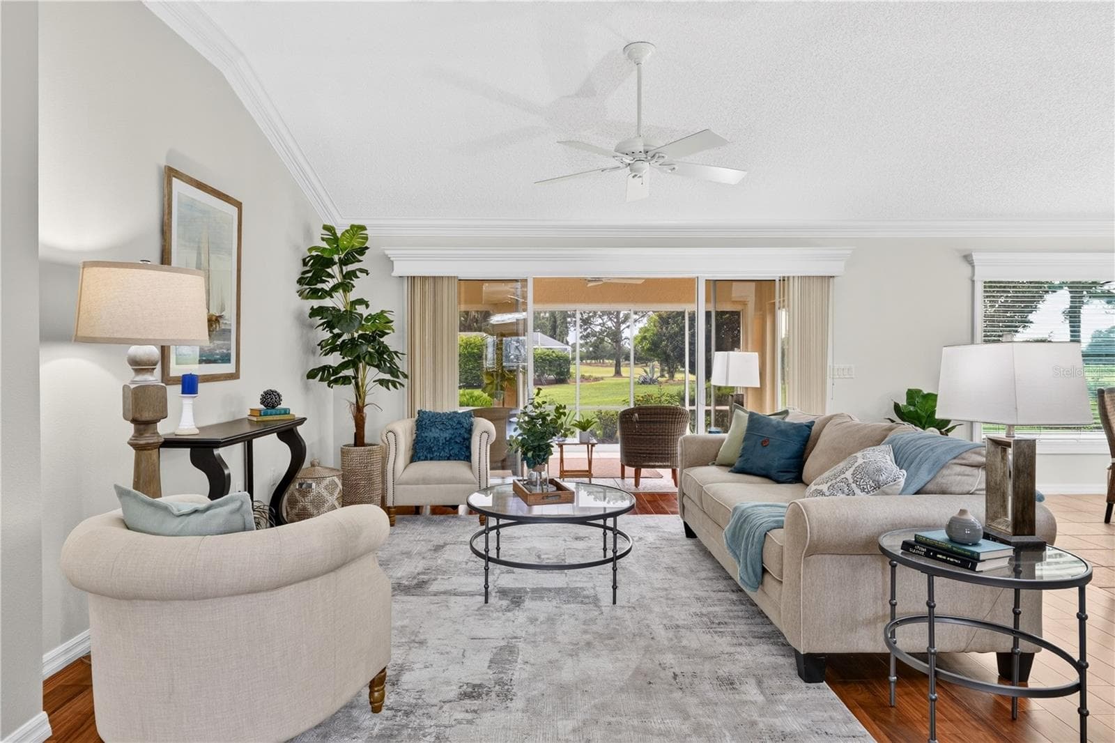 Light-filled living room with comfortable gathering space, high ceilings, and large windows overlooking the outdoor views. - 16815 SE 85TH BELKNAP AVE, THE VILLAGES
