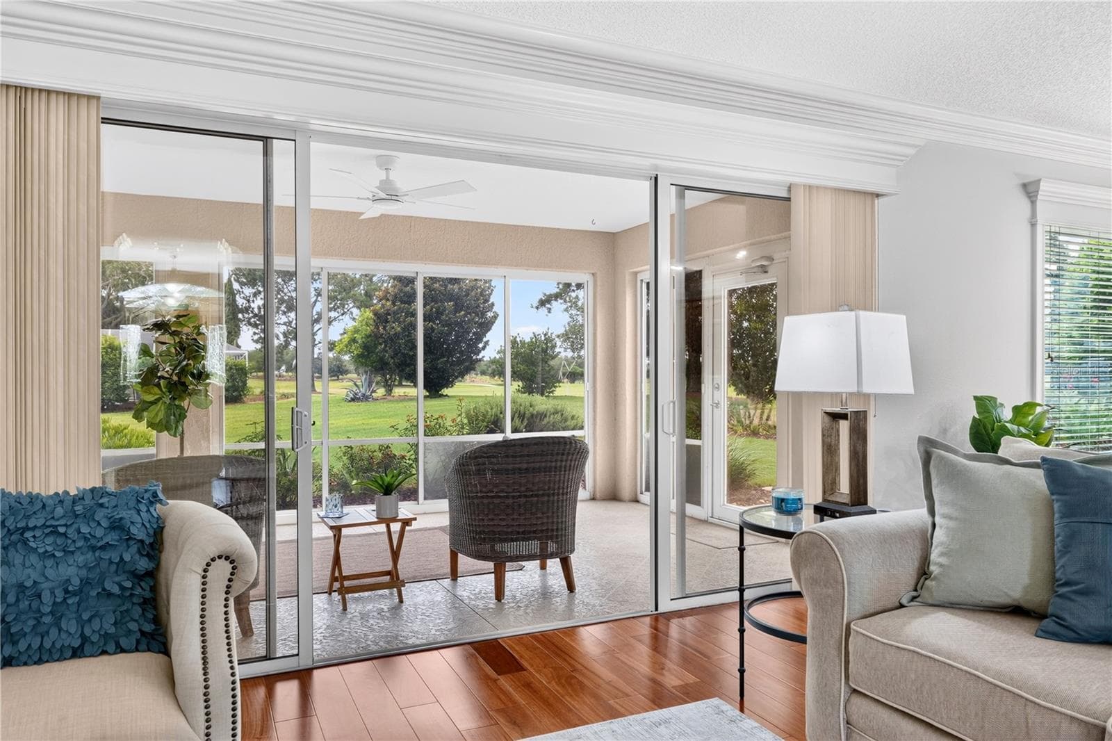 Living area with sliding glass doors opening to the enclosed lanai and peaceful green views beyond. - 16815 SE 85TH BELKNAP AVE, THE VILLAGES