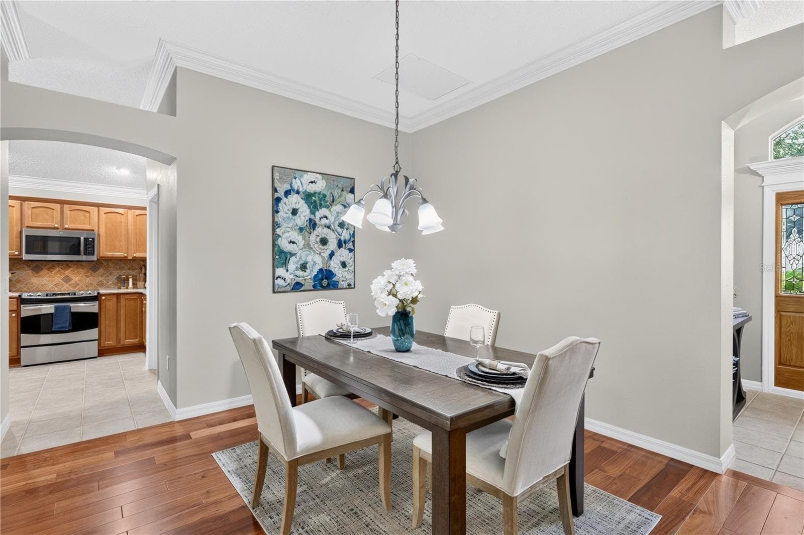Dining area with elegant lighting, wood flooring, and convenient access to the kitchen through the arched opening. - 16815 SE 85TH BELKNAP AVE, THE VILLAGES