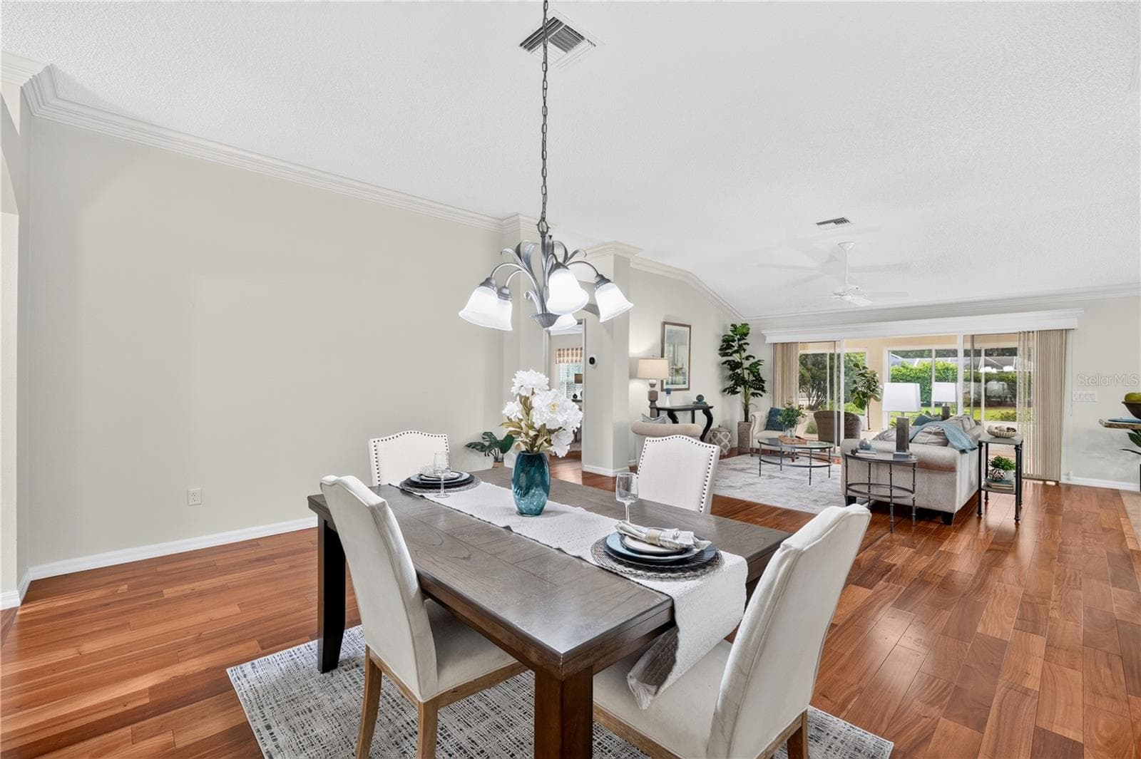 Formal dining space with rich wood flooring, neutral wall color, and an open sightline into the living room. - 16815 SE 85TH BELKNAP AVE, THE VILLAGES