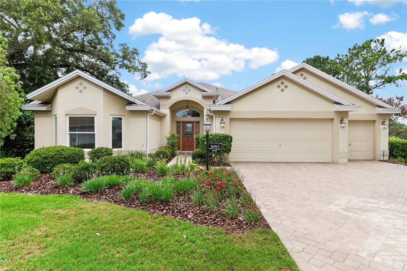 Welcoming front exterior with a spacious driveway, two-car garage, arched entryway, and well-maintained landscaping. - 16815 SE 85TH BELKNAP AVE, THE VILLAGES
