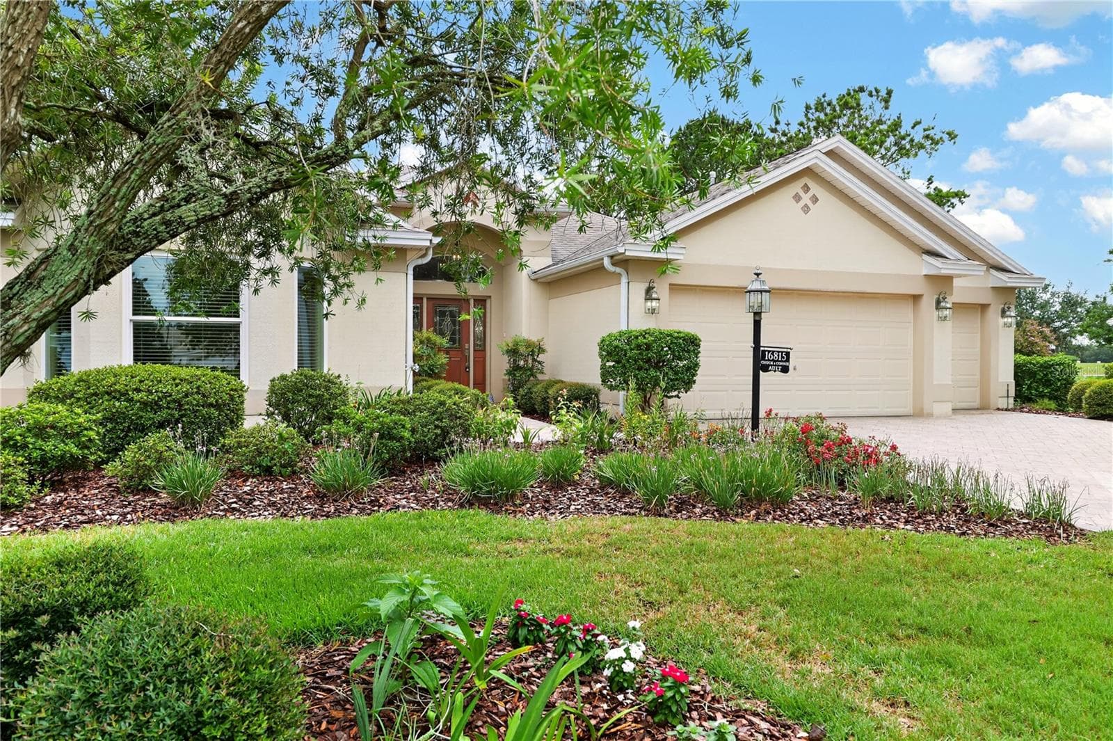 Charming front exterior framed by colorful landscaping, mature trees, and a beautifully maintained lawn. - 16815 SE 85TH BELKNAP AVE, THE VILLAGES