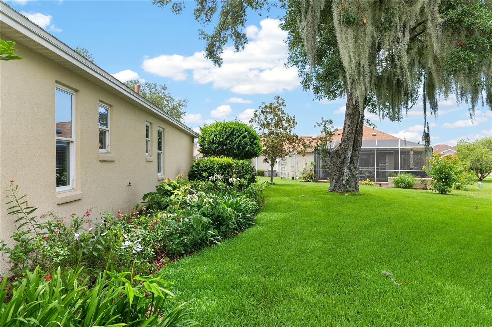 Beautifully maintained side yard with mature trees, established landscaping, and a private, peaceful feel. - 16815 SE 85TH BELKNAP AVE, THE VILLAGES