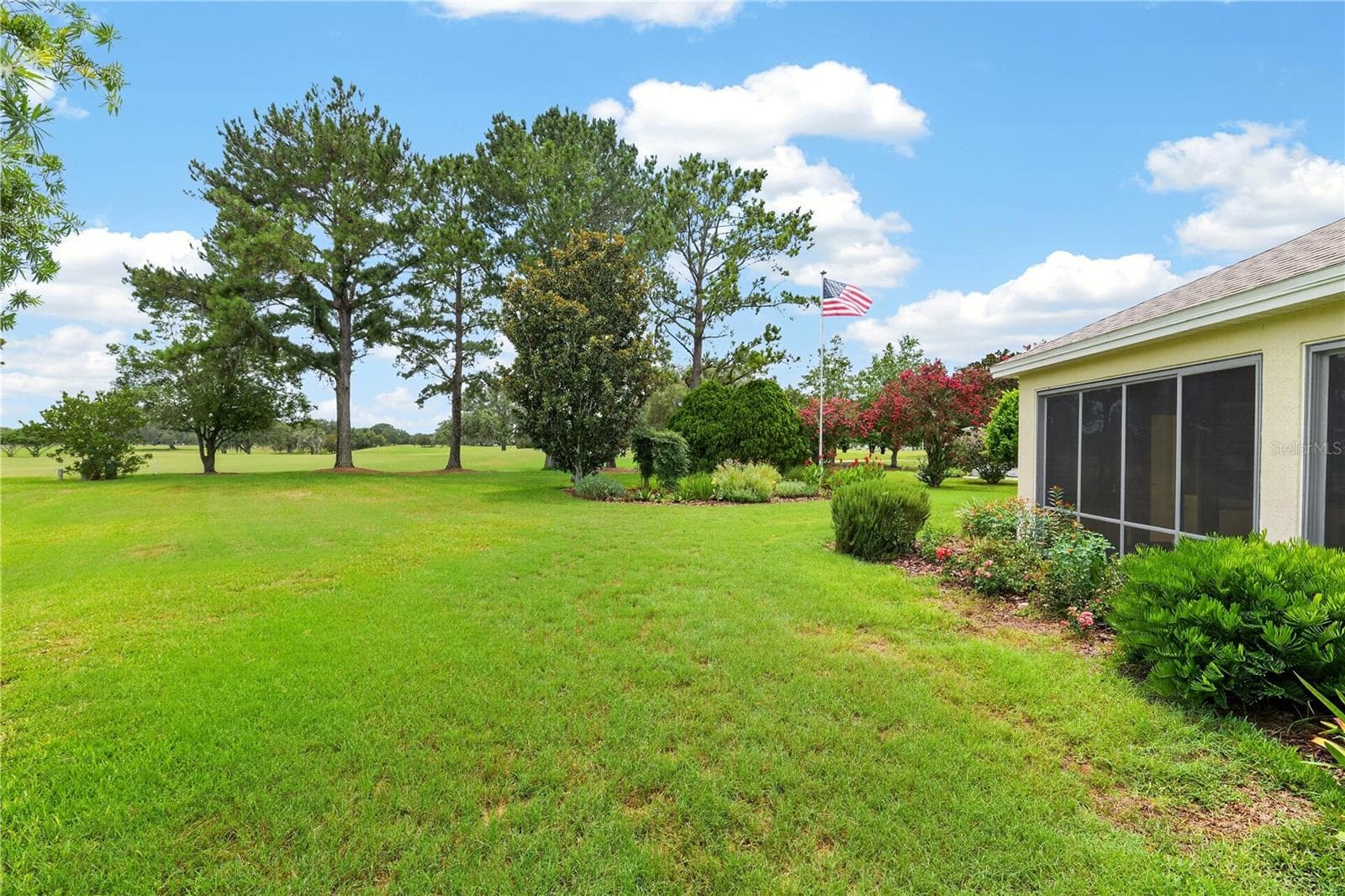 Rear lawn and garden view showcasing the home’s peaceful setting, mature trees, and scenic green space. - 16815 SE 85TH BELKNAP AVE, THE VILLAGES
