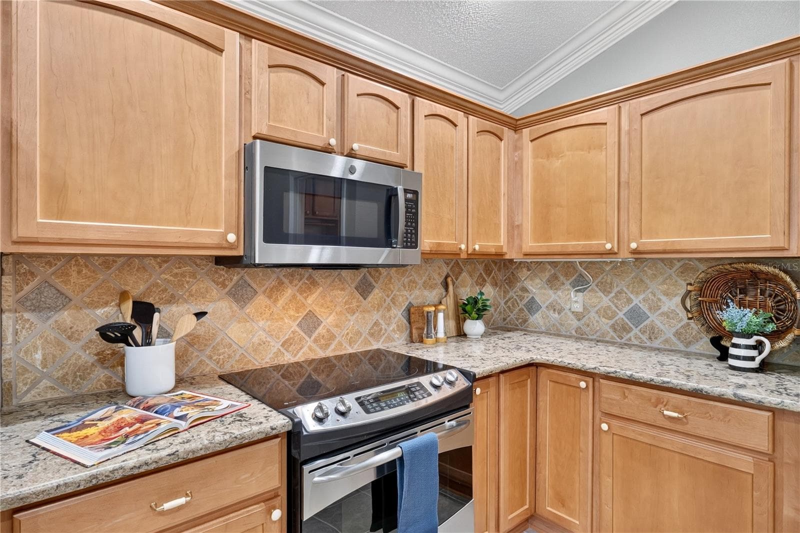 Functional kitchen layout with generous cabinet storage, neutral countertops, and a decorative tile backsplash. - 16815 SE 85TH BELKNAP AVE, THE VILLAGES