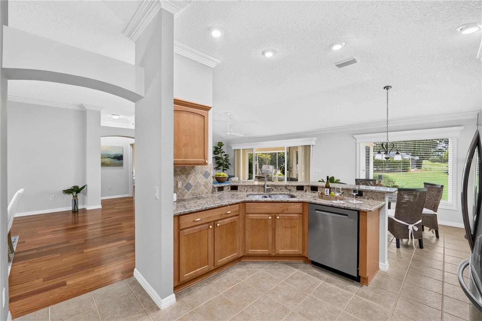 Kitchen view showcasing the open layout, generous counter space, stainless steel dishwasher, and convenient connection to the main living areas. - 16815 SE 85TH BELKNAP AVE, THE VILLAGES