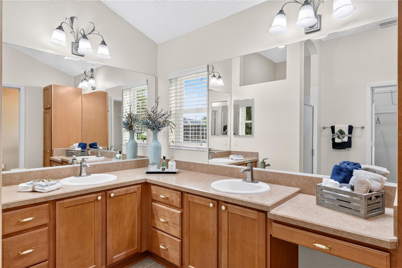 Dual-sink vanity with wood cabinetry, large mirrors, and excellent storage in the primary bath. - 16815 SE 85TH BELKNAP AVE, THE VILLAGES