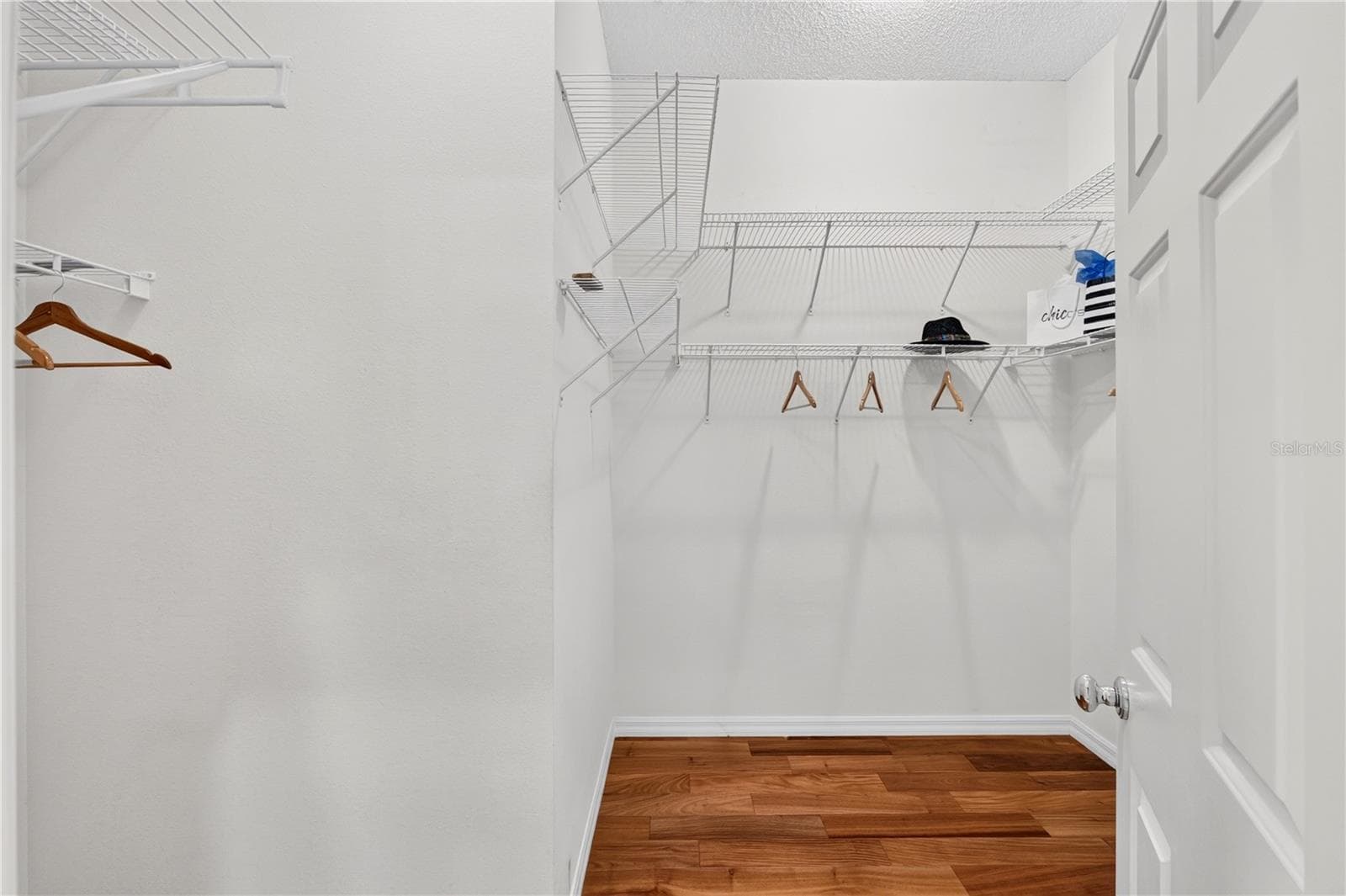 Large walk-in closet with wood flooring, wire shelving, and excellent storage capacity. - 16815 SE 85TH BELKNAP AVE, THE VILLAGES