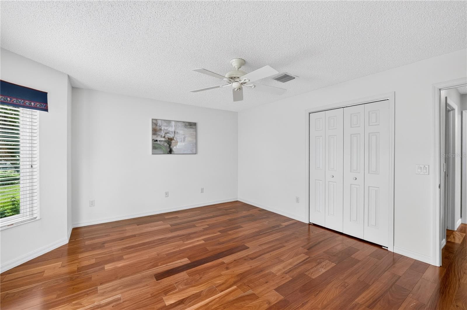 Guest bedroom with wood flooring, ceiling fan, closet storage, and a clean, neutral design. - 16815 SE 85TH BELKNAP AVE, THE VILLAGES