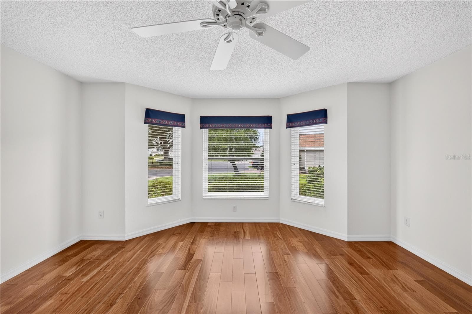 Bright guest bedroom featuring multiple windows, neutral walls, wood flooring, and peaceful outdoor views. - 16815 SE 85TH BELKNAP AVE, THE VILLAGES