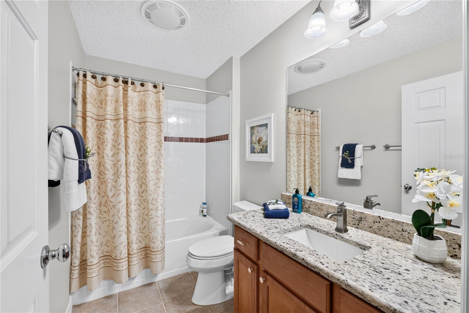 Guest bathroom with tub/shower combination, QUARTZ Counter, wood vanity, large mirror, and neutral finishes. - 16815 SE 85TH BELKNAP AVE, THE VILLAGES
