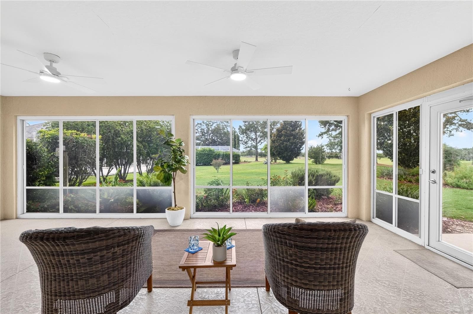 Enclosed lanai with expansive windows, ceiling fan, and beautiful views of the green space and mature landscaping. - 16815 SE 85TH BELKNAP AVE, THE VILLAGES