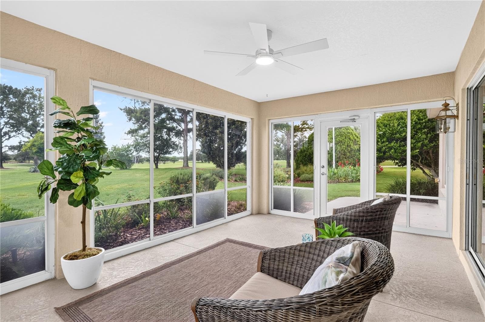 Spacious enclosed lanai with tile flooring, ceiling fan, and walls of windows overlooking the peaceful green space. - 16815 SE 85TH BELKNAP AVE, THE VILLAGES
