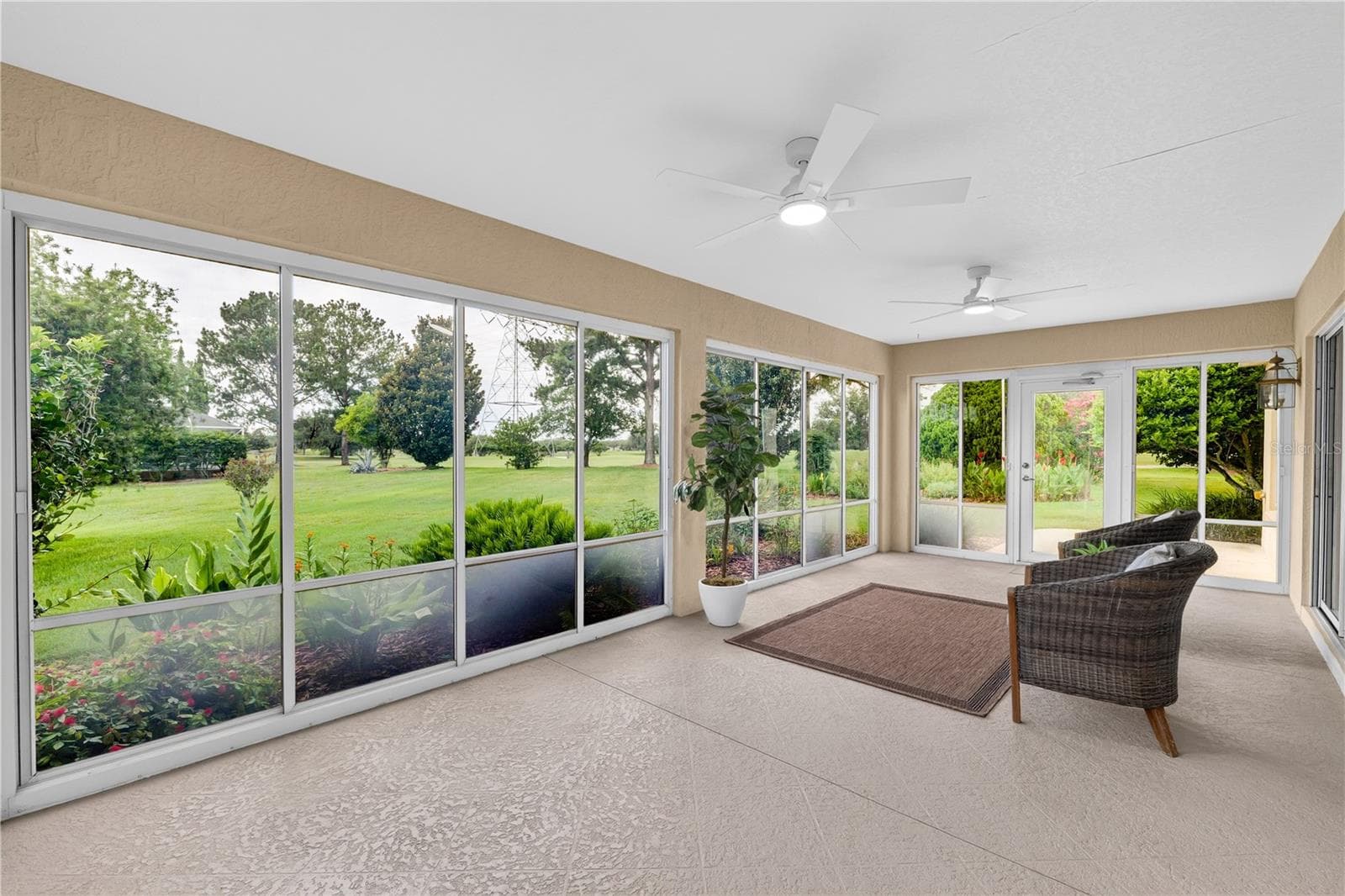 Enclosed lanai with walls of windows, ceiling fan, and serene views of the lush landscaping and open green space. - 16815 SE 85TH BELKNAP AVE, THE VILLAGES
