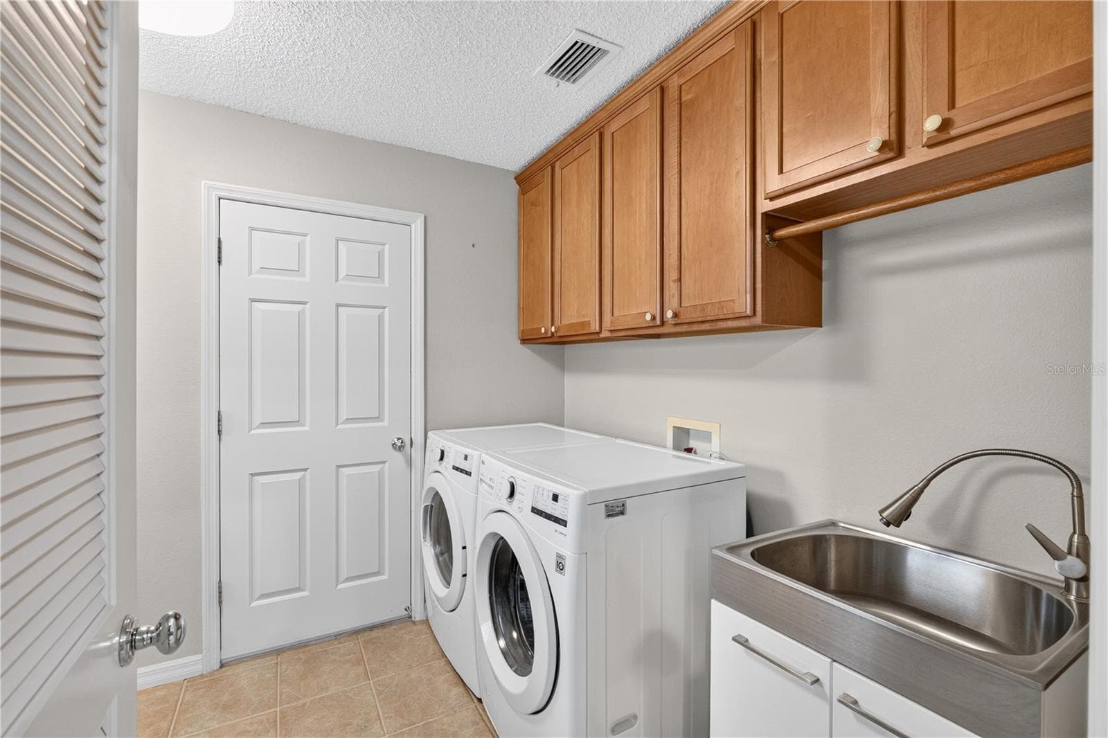 Interior laundry room with washer and dryer, upper cabinetry, utility sink, and convenient storage. - 16815 SE 85TH BELKNAP AVE, THE VILLAGES