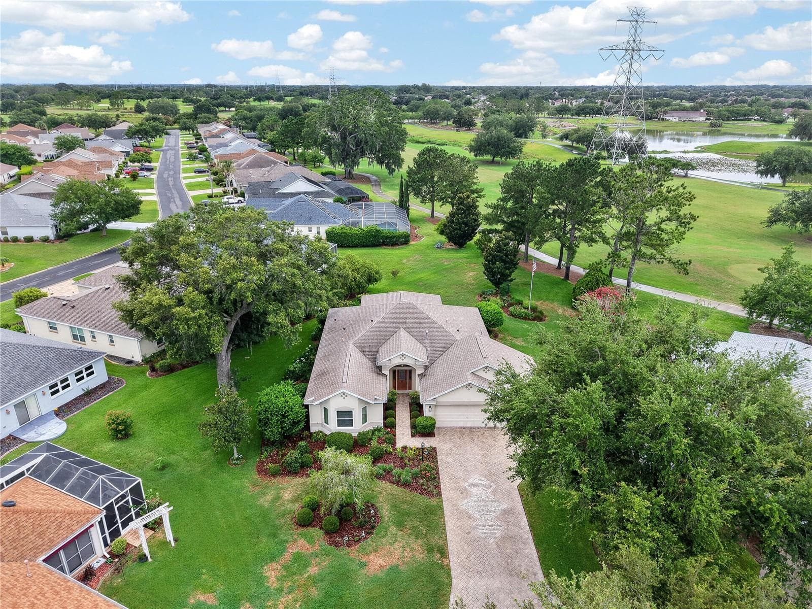 Aerial view showcasing the home’s beautiful setting, mature trees, long driveway, and nearby golf course views. - 16815 SE 85TH BELKNAP AVE, THE VILLAGES