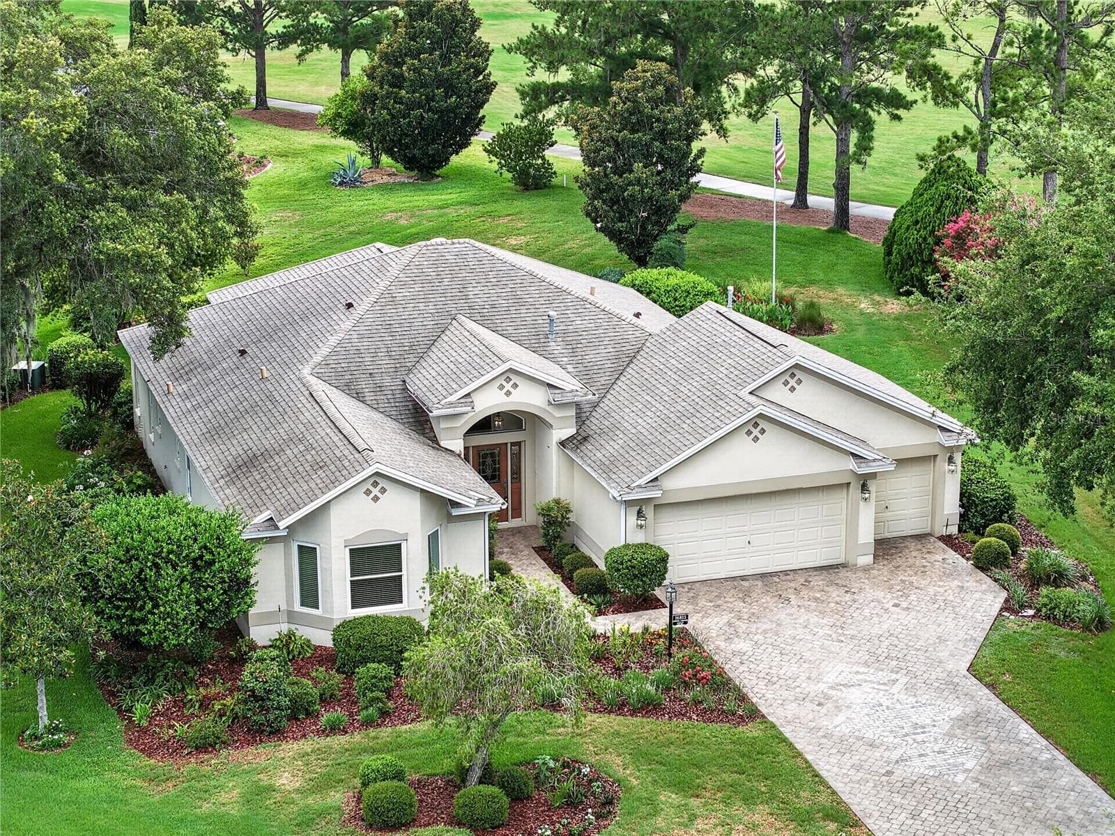 Elevated front view highlighting the home’s curb appeal, lush greenery, and desirable lot position surrounded by mature trees. - 16815 SE 85TH BELKNAP AVE, THE VILLAGES