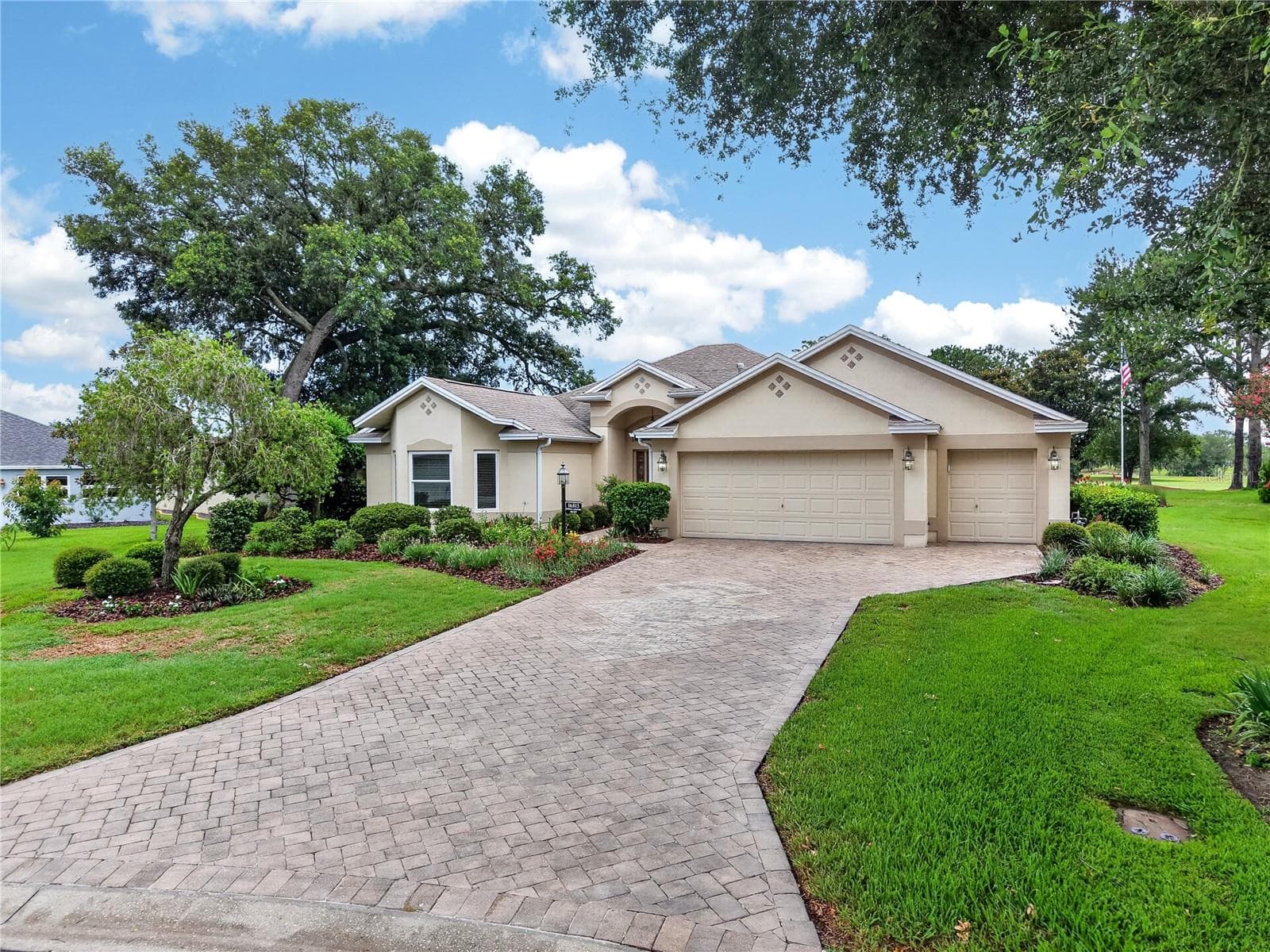 Wide driveway approach with manicured lawn, mature shade trees, and an attractive front elevation. - 16815 SE 85TH BELKNAP AVE, THE VILLAGES