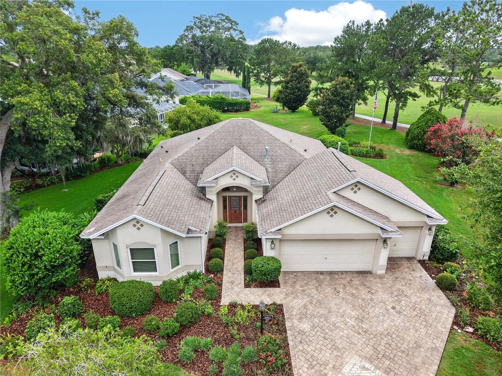 Beautiful aerial view showcasing the home’s attractive roofline, mature landscaping, and peaceful setting with golf course views beyond. - 16815 SE 85TH BELKNAP AVE, THE VILLAGES